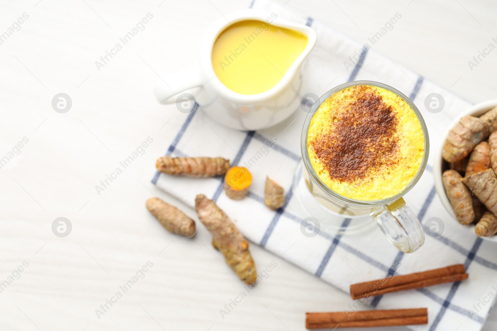 Photo of Delicious turmeric latte and rhizomes on white wooden table, flat lay. Space for text