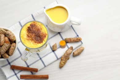 Photo of Delicious turmeric latte and rhizomes on white wooden table, flat lay. Space for text