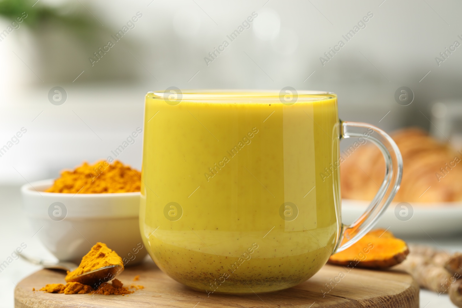 Photo of Delicious turmeric latte, powder and rhizomes on table, closeup