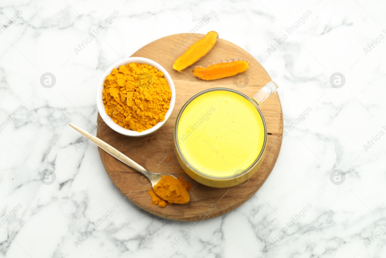 Photo of Delicious turmeric latte, powder and rhizomes on white marble table, top view