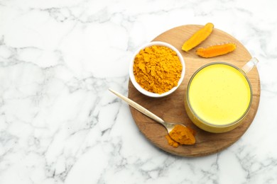 Photo of Delicious turmeric latte, powder and rhizomes on white marble table, top view. Space for text