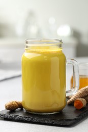 Photo of Delicious turmeric latte with honey and rhizomes on grey table, closeup