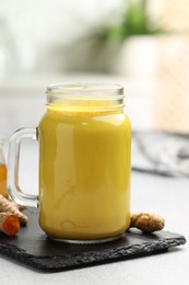 Photo of Delicious turmeric latte and rhizomes on grey table