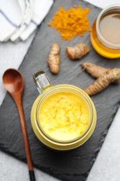 Photo of Delicious turmeric latte with honey, powder and rhizomes on grey table, flat lay