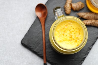 Photo of Delicious turmeric latte with honey and rhizomes on grey table, top view