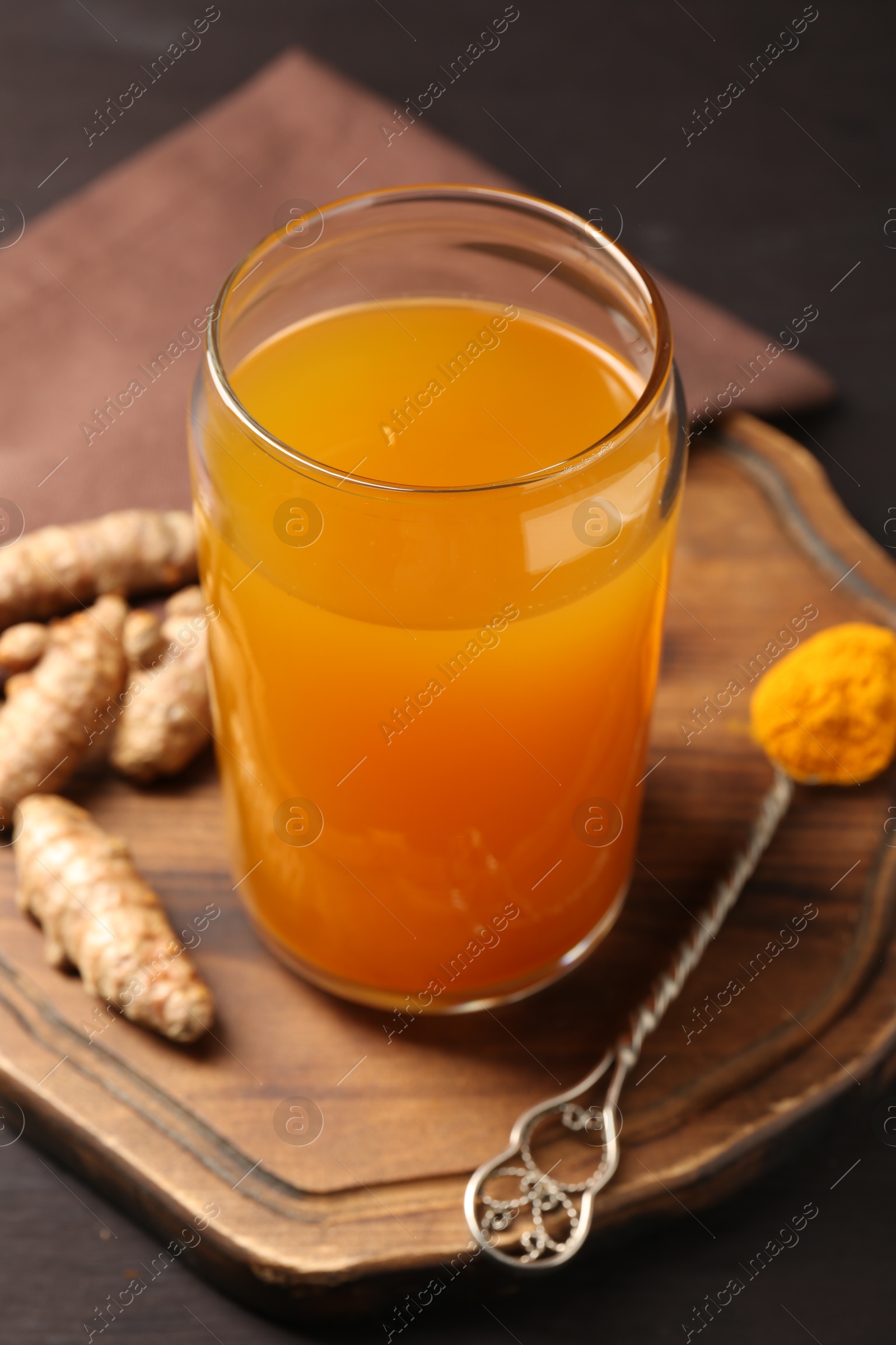 Photo of Aromatic turmeric tea in glass, roots and powder on table, closeup