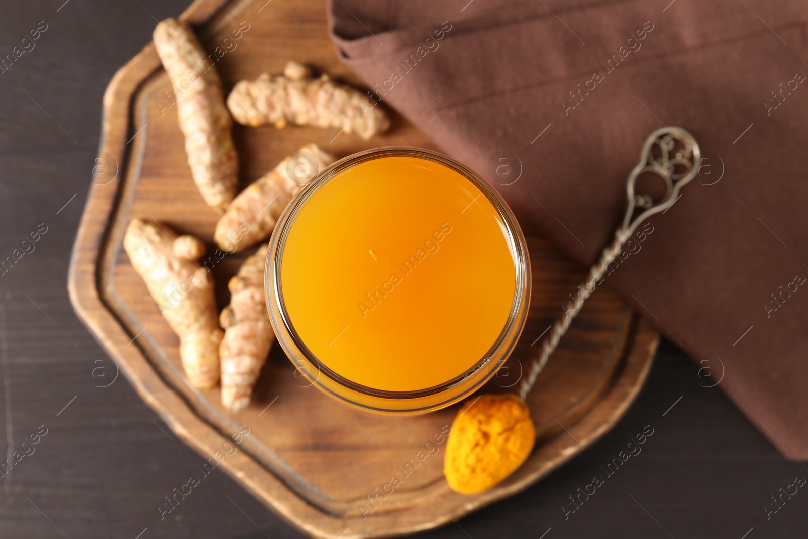 Photo of Aromatic turmeric tea in glass, roots and powder on wooden table, top view