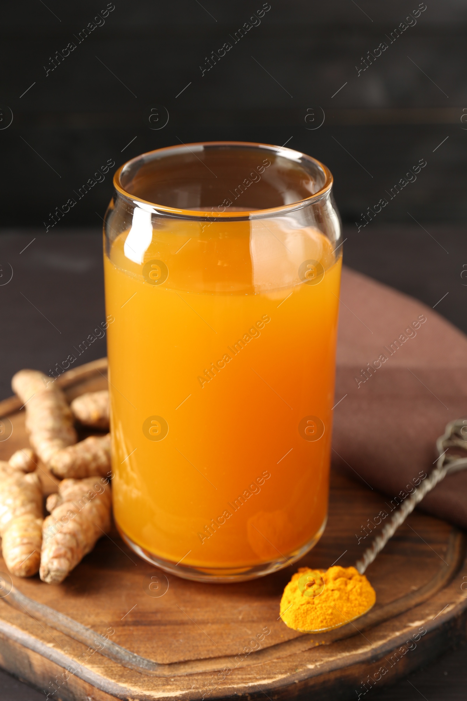 Photo of Aromatic turmeric tea in glass, roots and powder on table, closeup