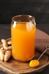 Photo of Aromatic turmeric tea in glass, roots and powder on table, closeup