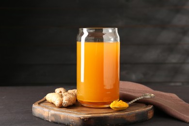 Photo of Aromatic turmeric tea in glass, roots and powder on wooden table