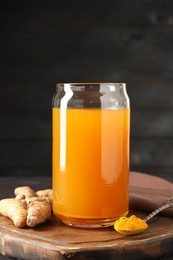 Photo of Aromatic turmeric tea in glass, roots and powder on table, closeup