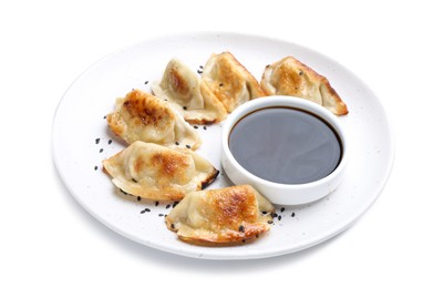 Photo of Delicious fried gyoza dumplings with sesame seeds and soy sauce isolated on white