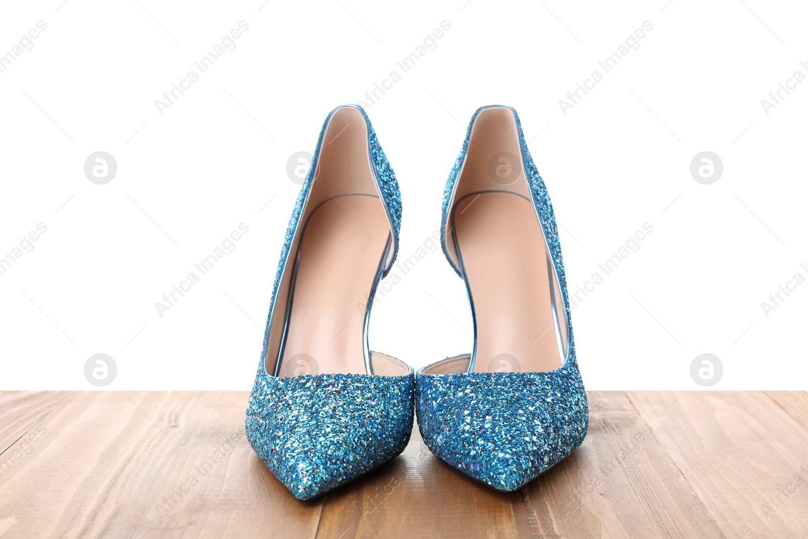 Photo of Beautiful high heeled shoes on wooden table against white background