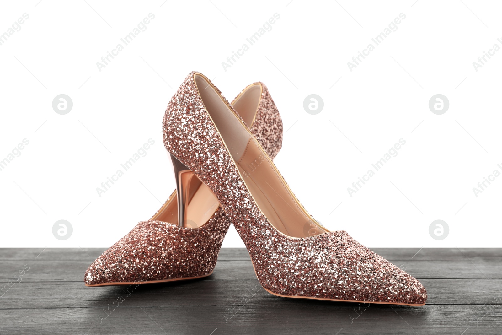 Photo of Beautiful high heeled shoes on black wooden table against white background