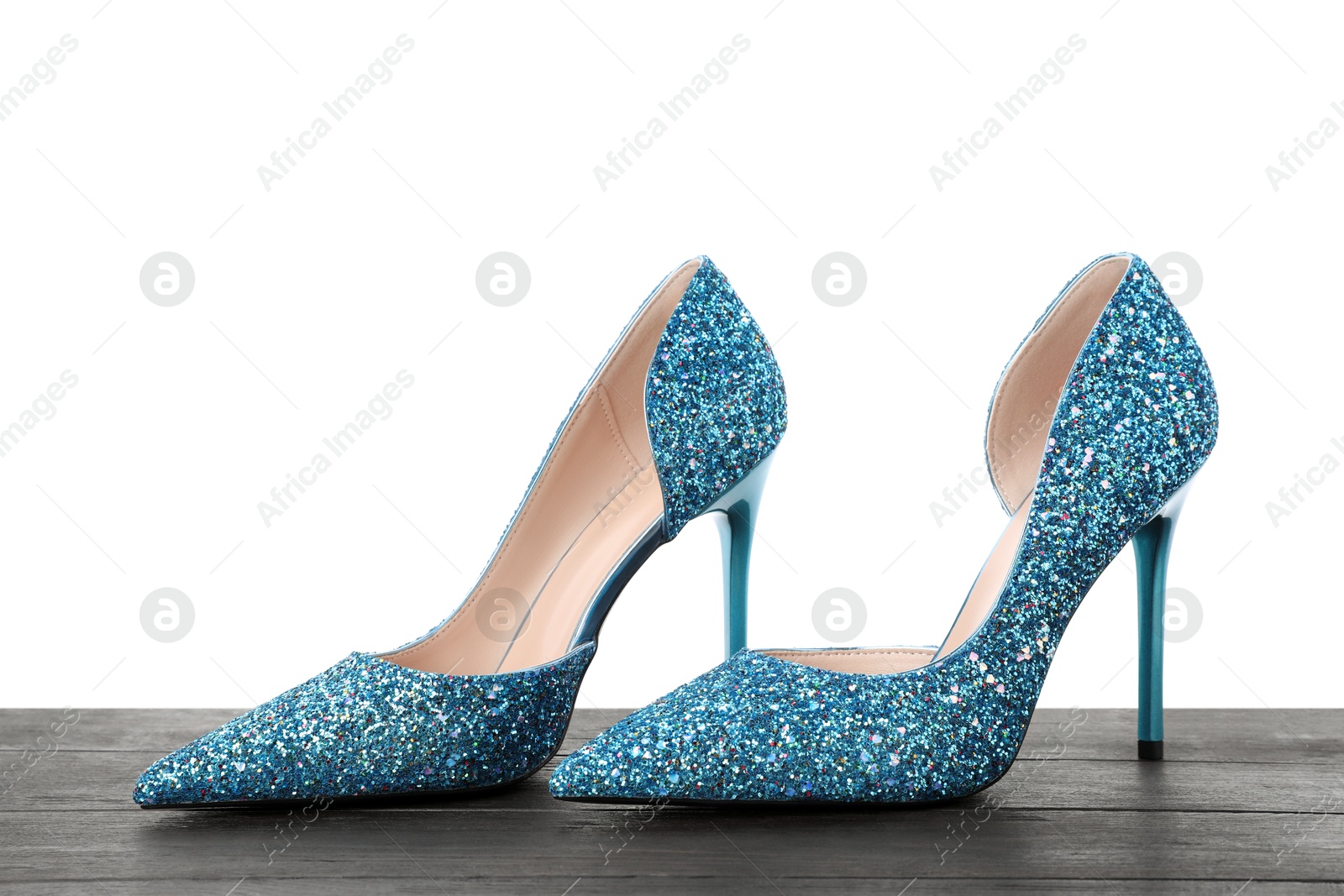 Photo of Beautiful high heeled shoes on black wooden table against white background