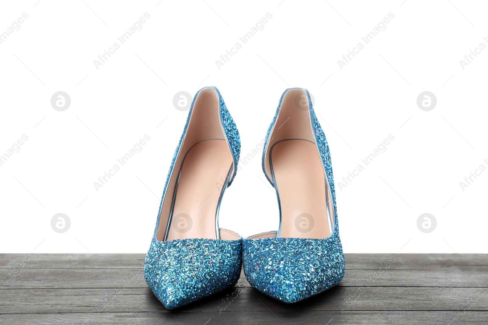 Photo of Beautiful high heeled shoes on black wooden table against white background