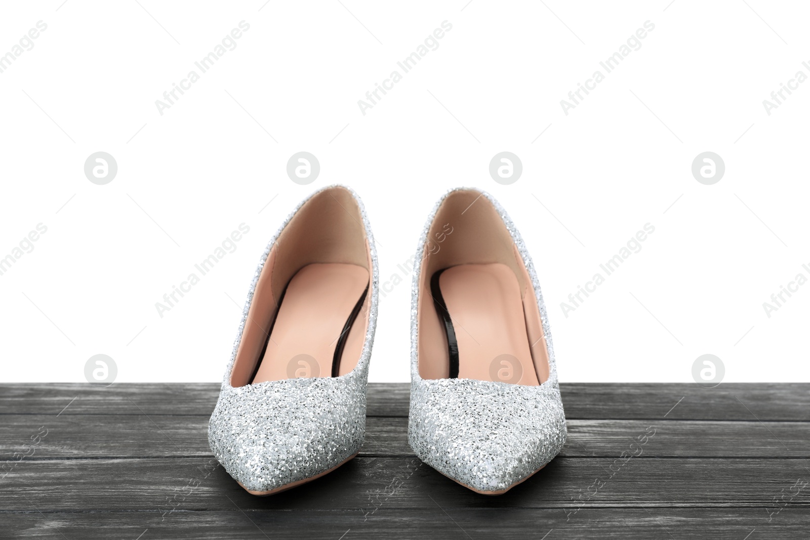 Photo of Beautiful high heeled shoes on black wooden table against white background