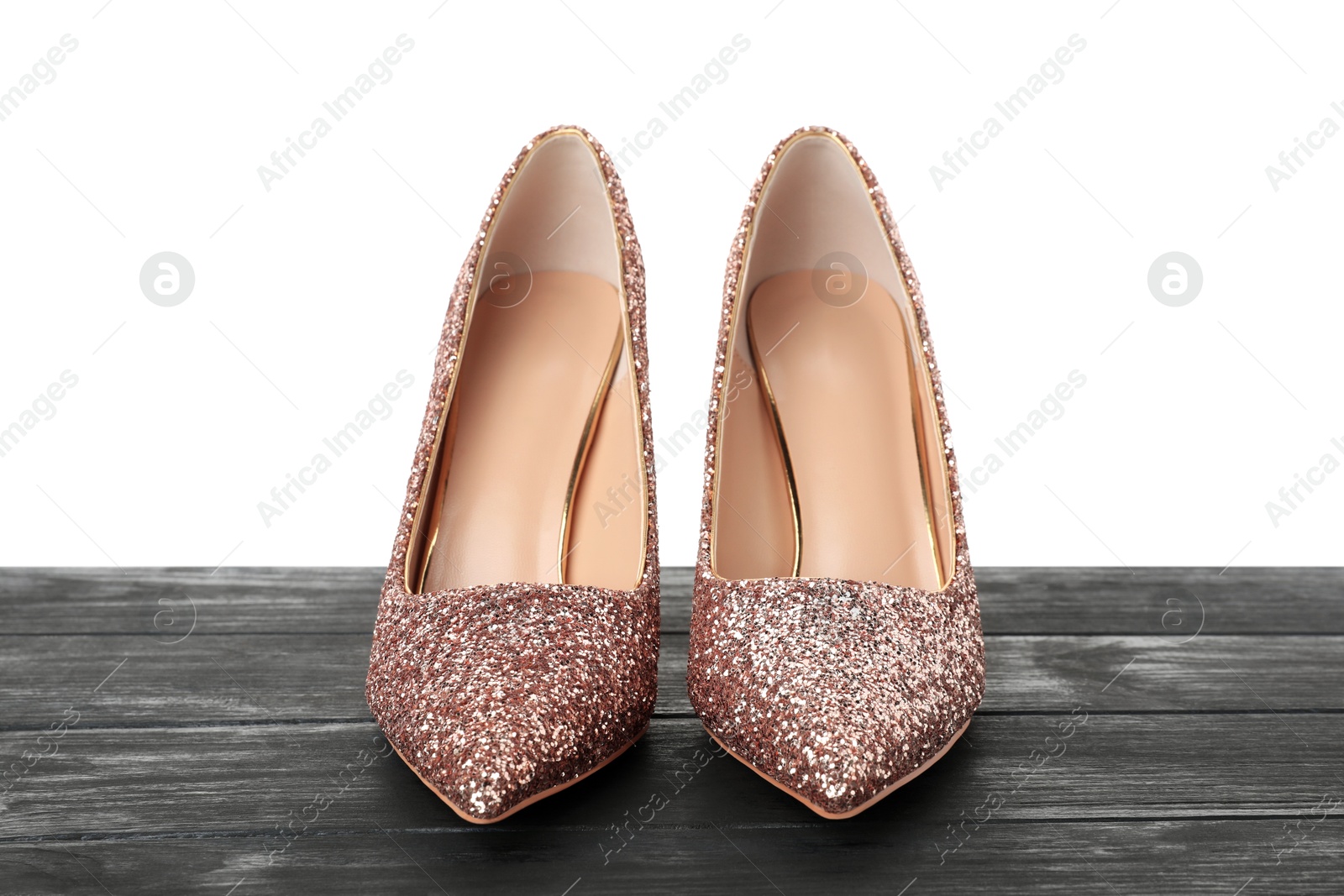 Photo of Beautiful high heeled shoes on black wooden table against white background