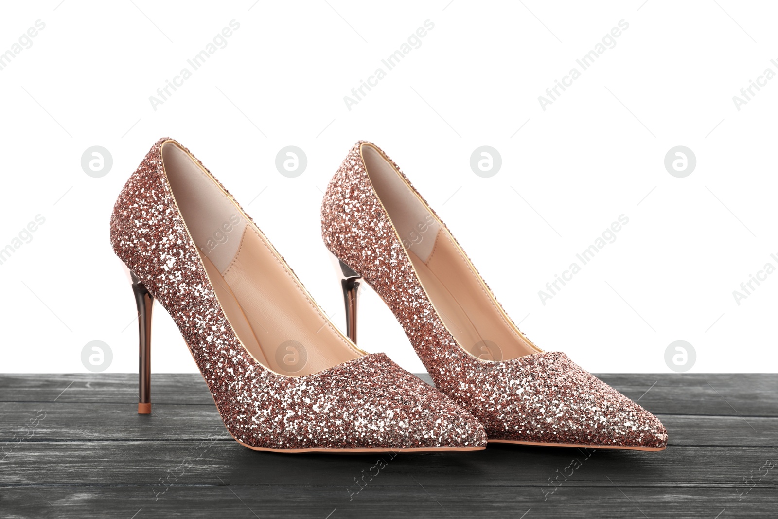 Photo of Beautiful high heeled shoes on black wooden table against white background