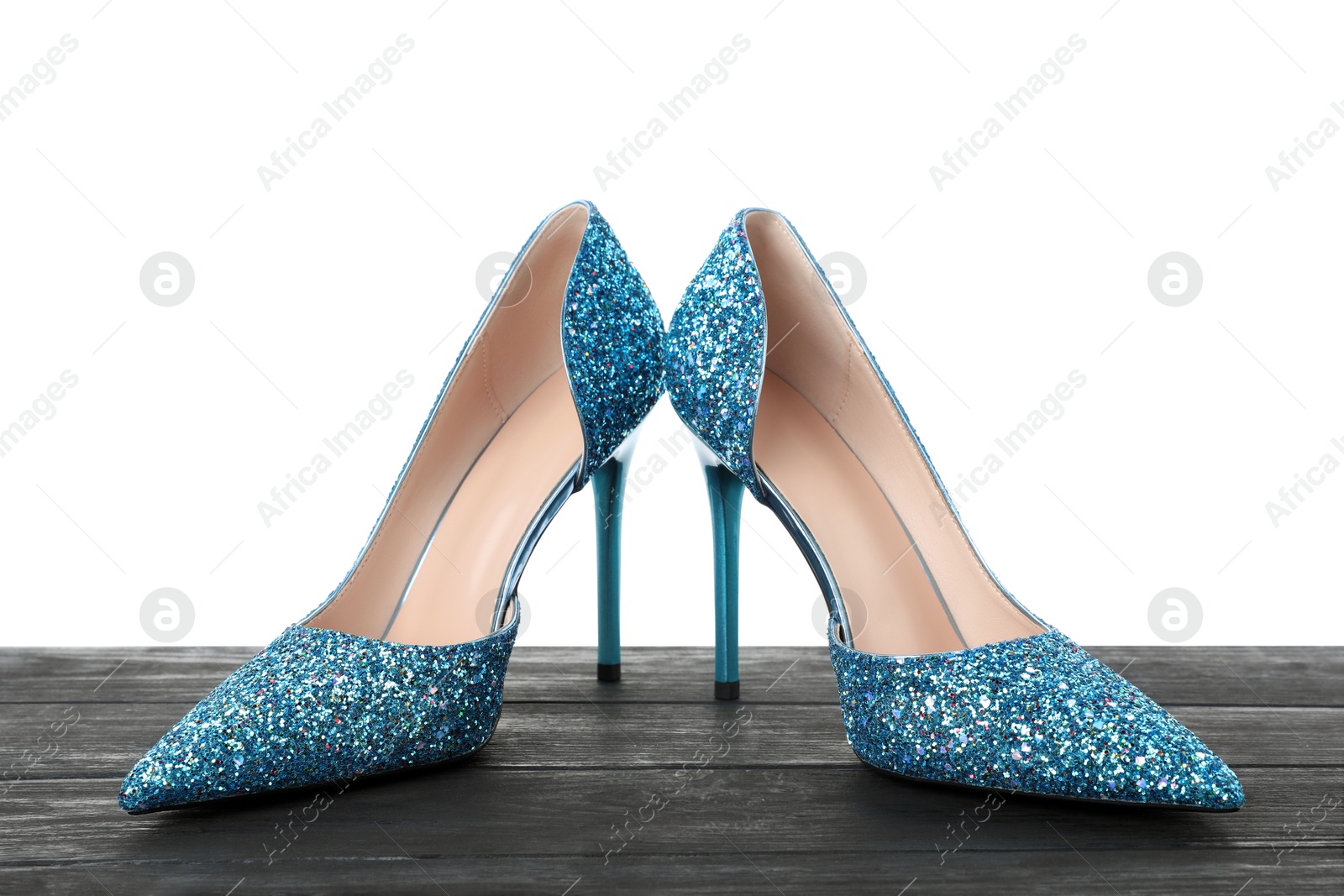 Photo of Beautiful high heeled shoes on black wooden table against white background