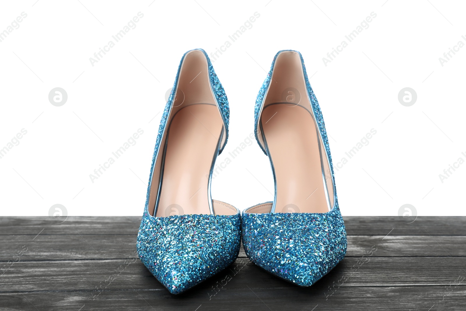 Photo of Beautiful high heeled shoes on black wooden table against white background