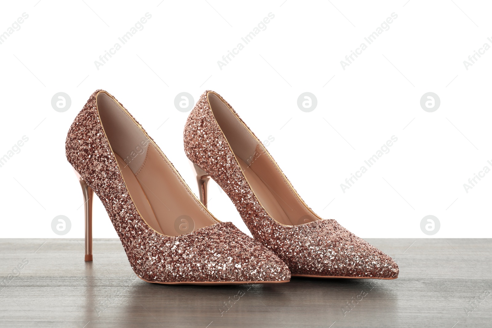 Photo of Beautiful high heeled shoes on wooden table against white background