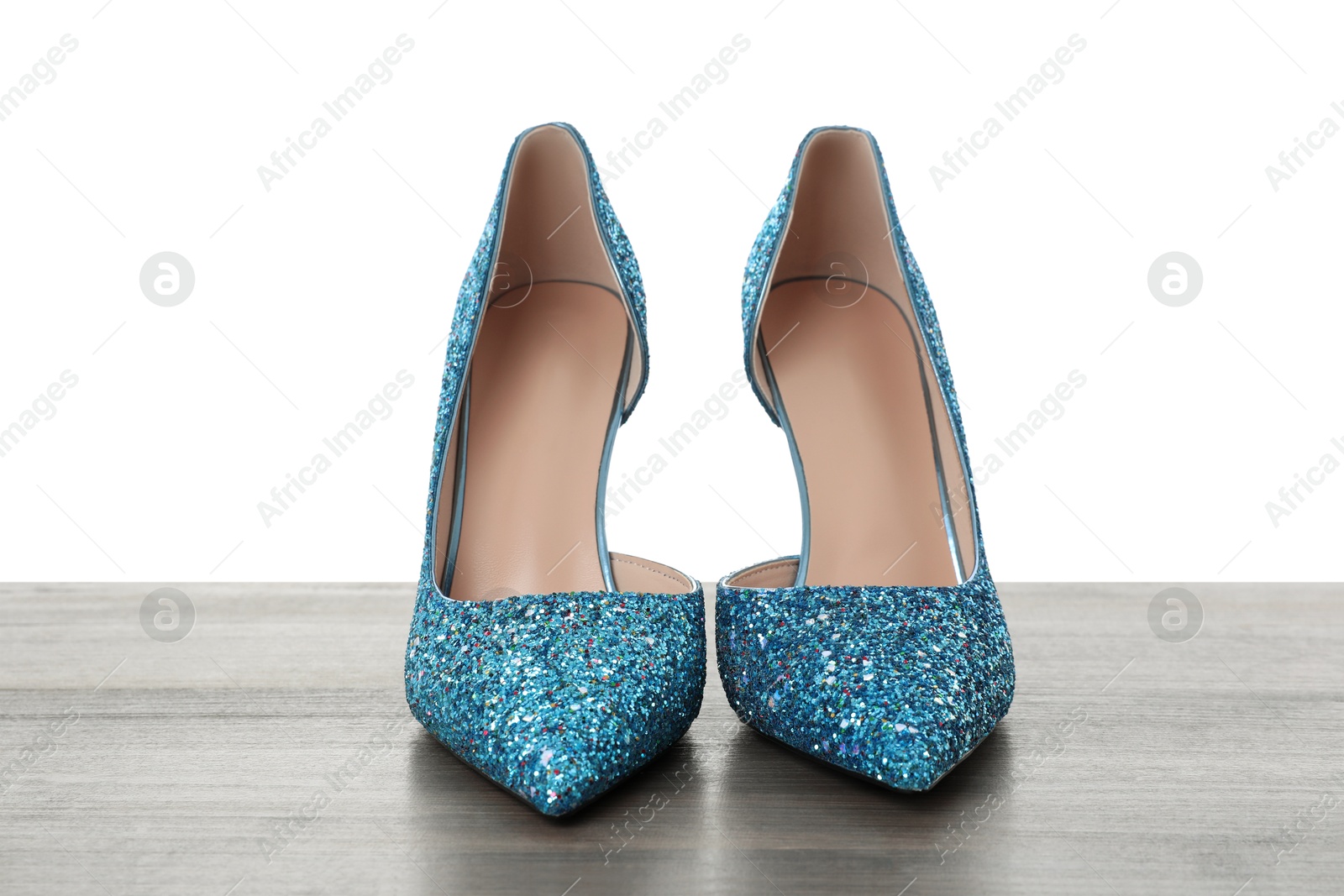 Photo of Beautiful high heeled shoes on wooden table against white background