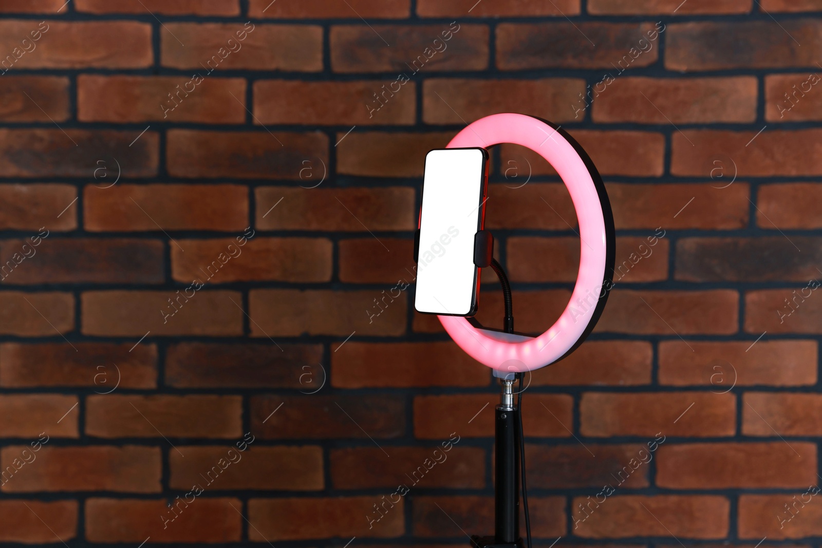 Photo of Ring lamp with smartphone against brick wall, space for text