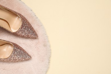 Shiny high heeled shoes and faux fur on beige background, top view. Space for text