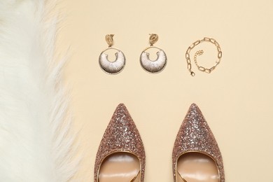 Photo of Fashionable composition with shiny high heeled shoes and accessories on beige background, flat lay