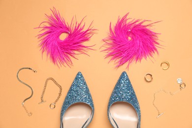 Photo of Fashionable composition with shiny high heeled shoes and accessories on pale orange background, flat lay