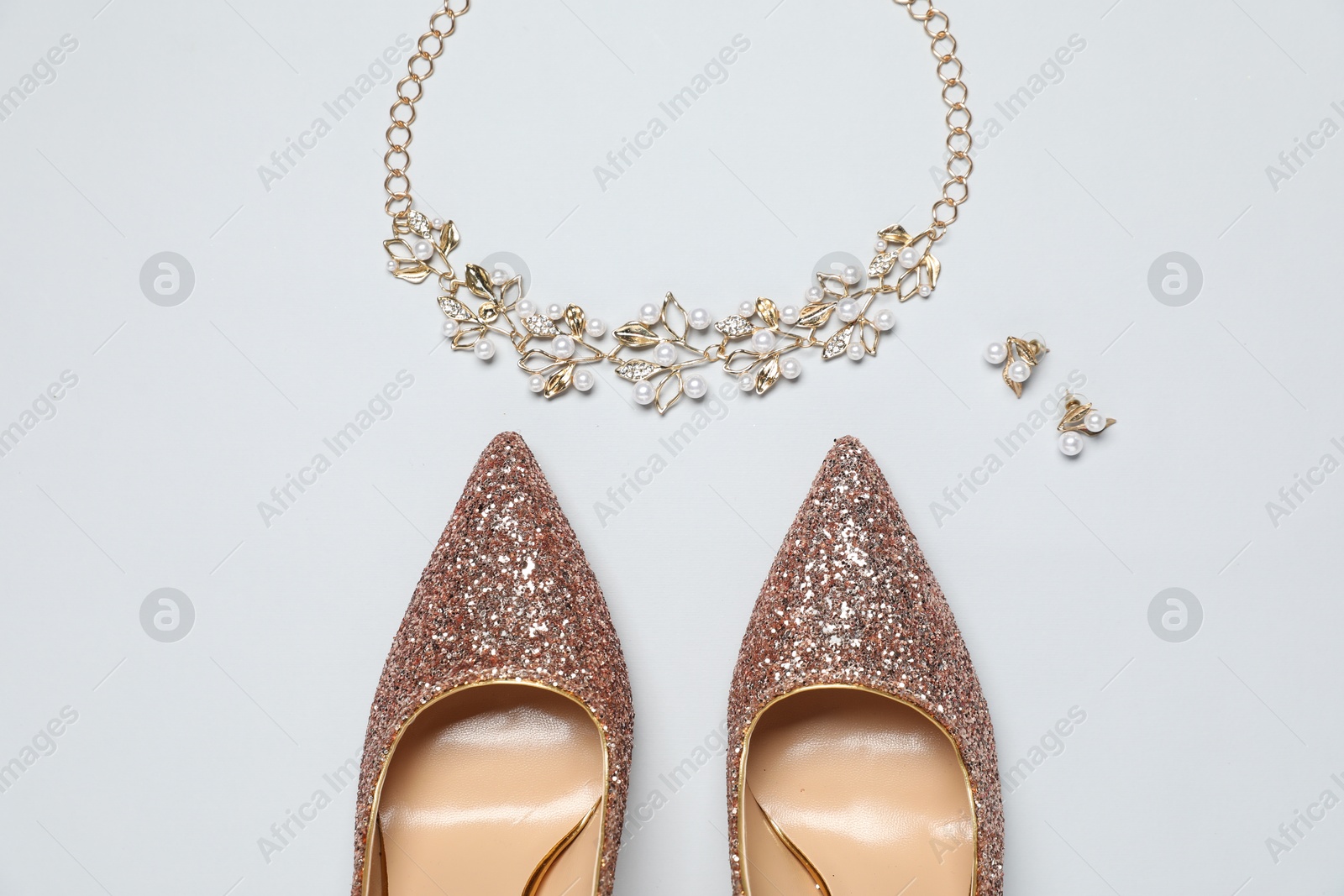 Photo of Shiny high heeled shoes and accessories on light grey background, flat lay