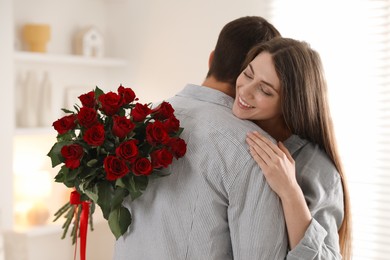 Photo of Lovely couple with bouquet of red roses indoors. Valentine's day celebration