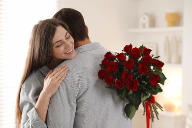 Photo of Lovely couple with bouquet of red roses indoors. Valentine's day celebration