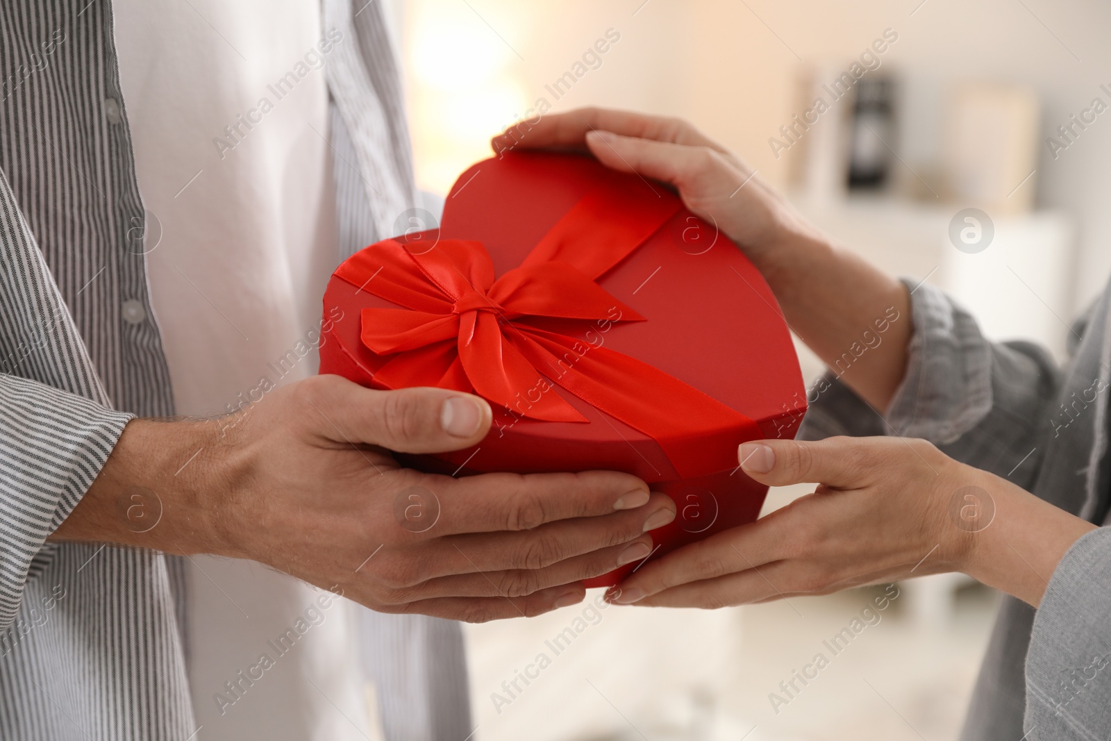 Photo of Lovely couple with gift box indoors, closeup. Valentine's day celebration