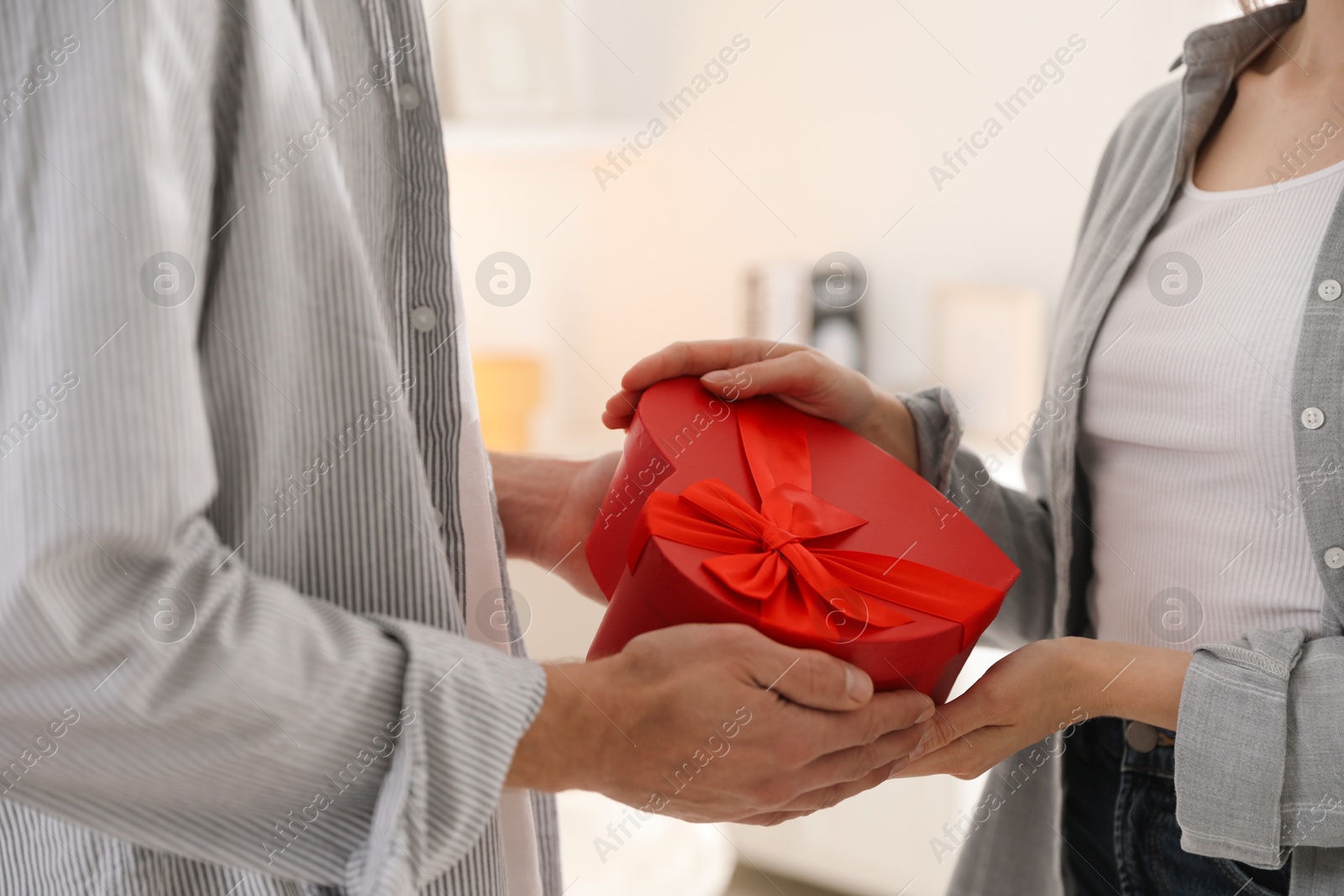 Photo of Lovely couple with gift box indoors, closeup. Valentine's day celebration