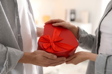 Photo of Lovely couple with gift box indoors, closeup. Valentine's day celebration