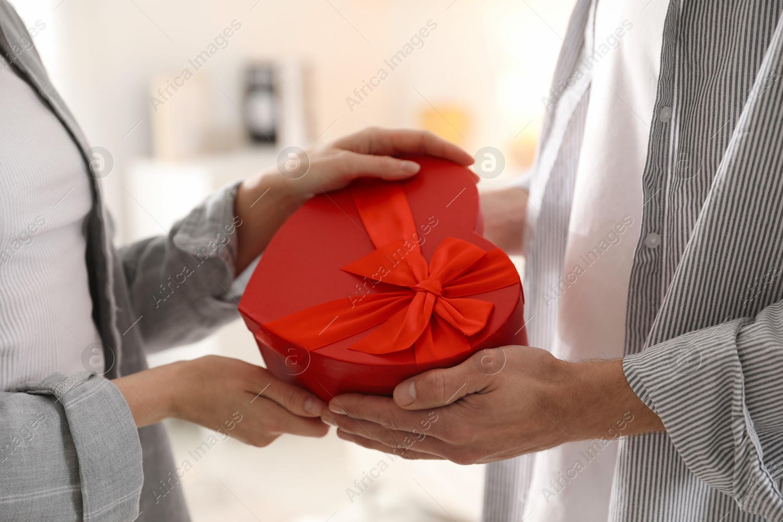 Photo of Lovely couple with gift box indoors, closeup. Valentine's day celebration