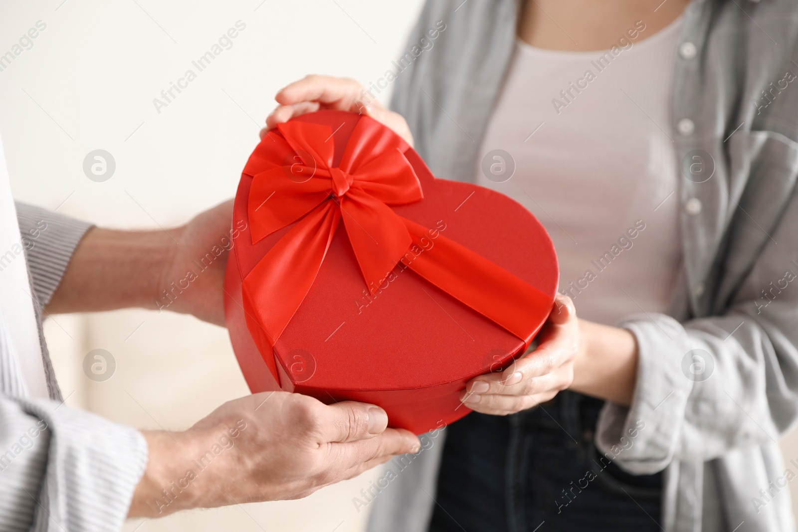 Photo of Lovely couple with gift box indoors, closeup. Valentine's day celebration