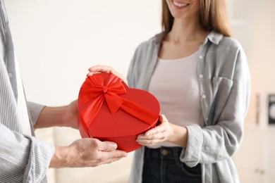 Photo of Lovely couple with gift box indoors, closeup. Valentine's day celebration