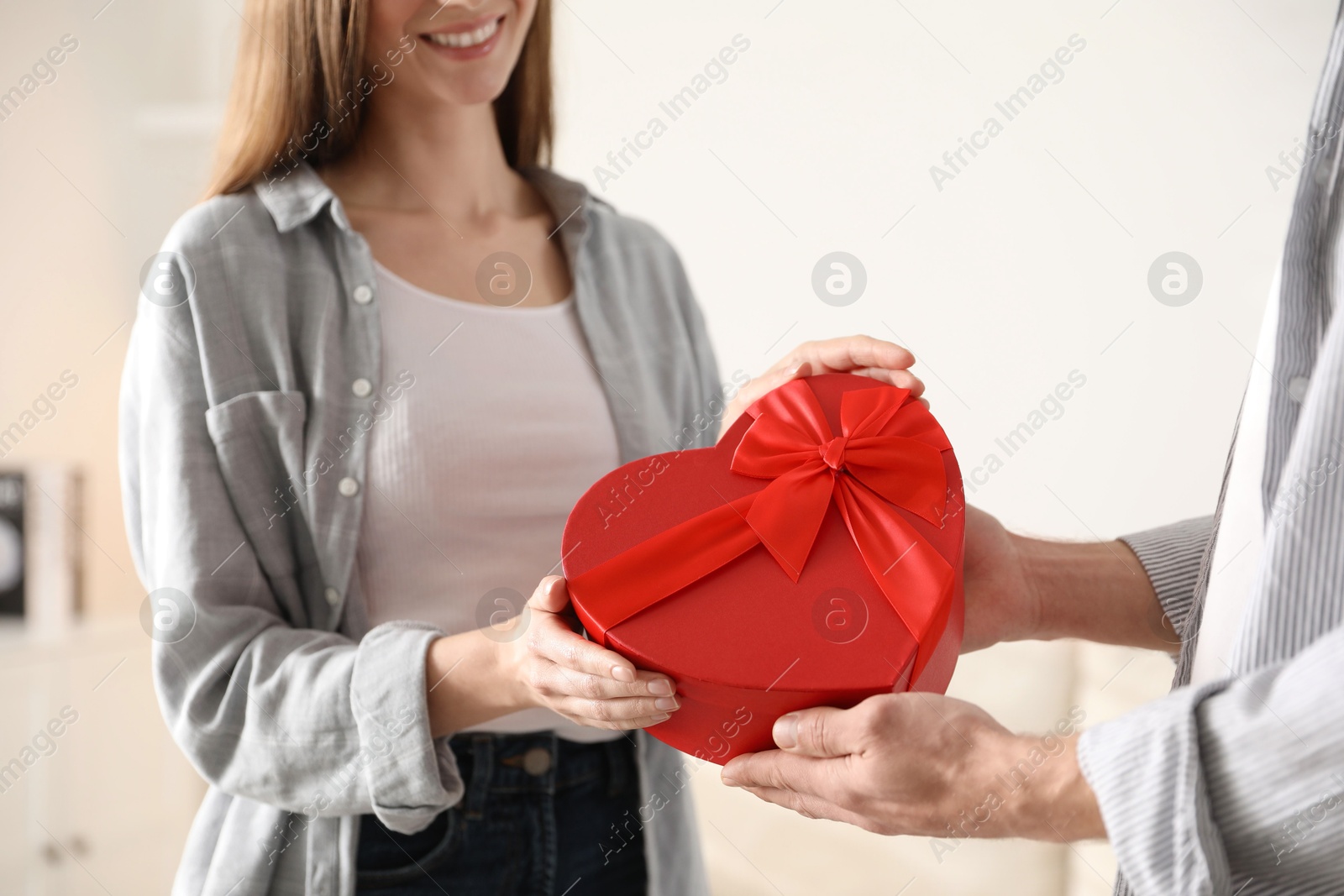 Photo of Lovely couple with gift box indoors, closeup. Valentine's day celebration