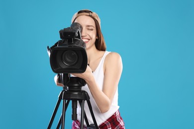 Photo of Happy woman with professional video camera on light blue background