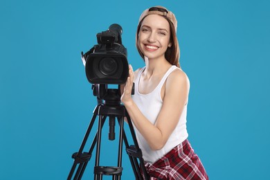 Photo of Happy woman with professional video camera on light blue background