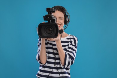 Photo of Happy woman with professional video camera and headset on light blue background