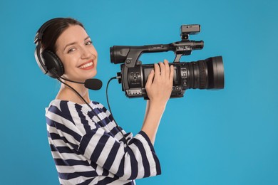 Photo of Happy woman with professional video camera and headset on light blue background