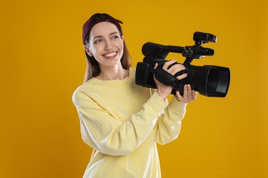 Photo of Happy woman with professional video camera on orange background