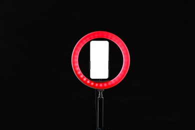 Photo of Ring lamp with smartphone on black background