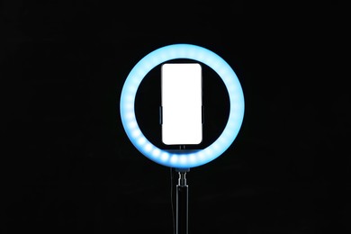 Photo of Ring lamp with smartphone on black background