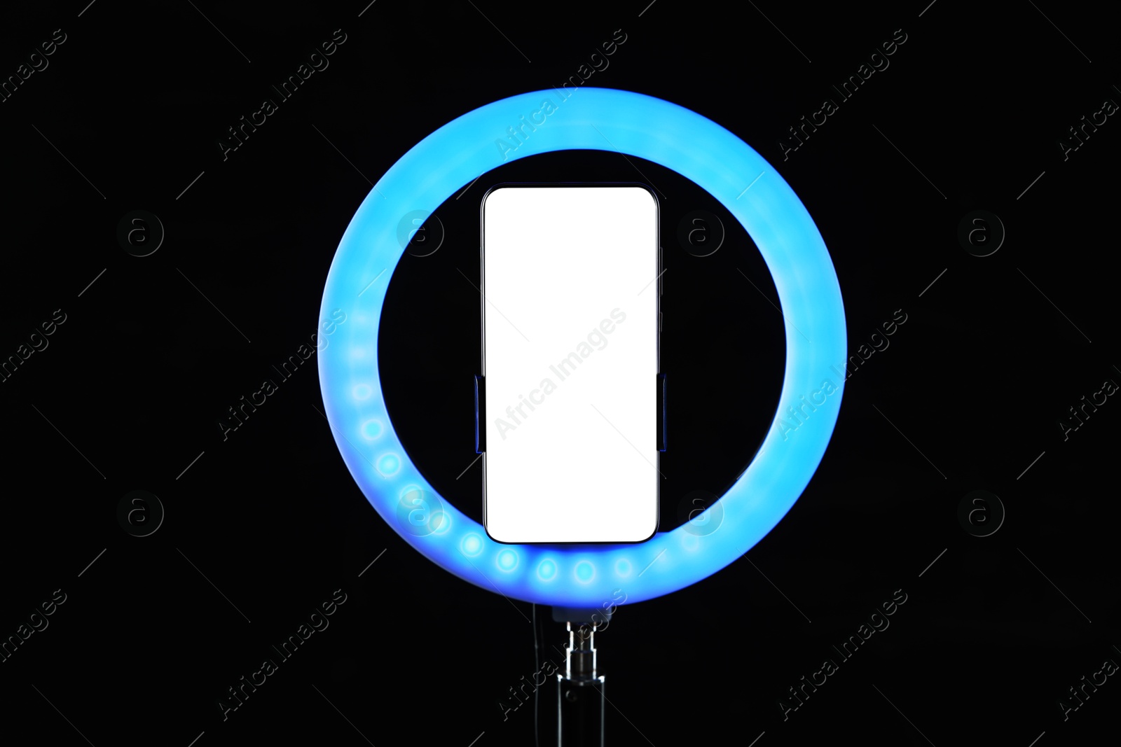 Photo of Ring lamp with smartphone on black background