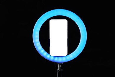 Photo of Ring lamp with smartphone on black background